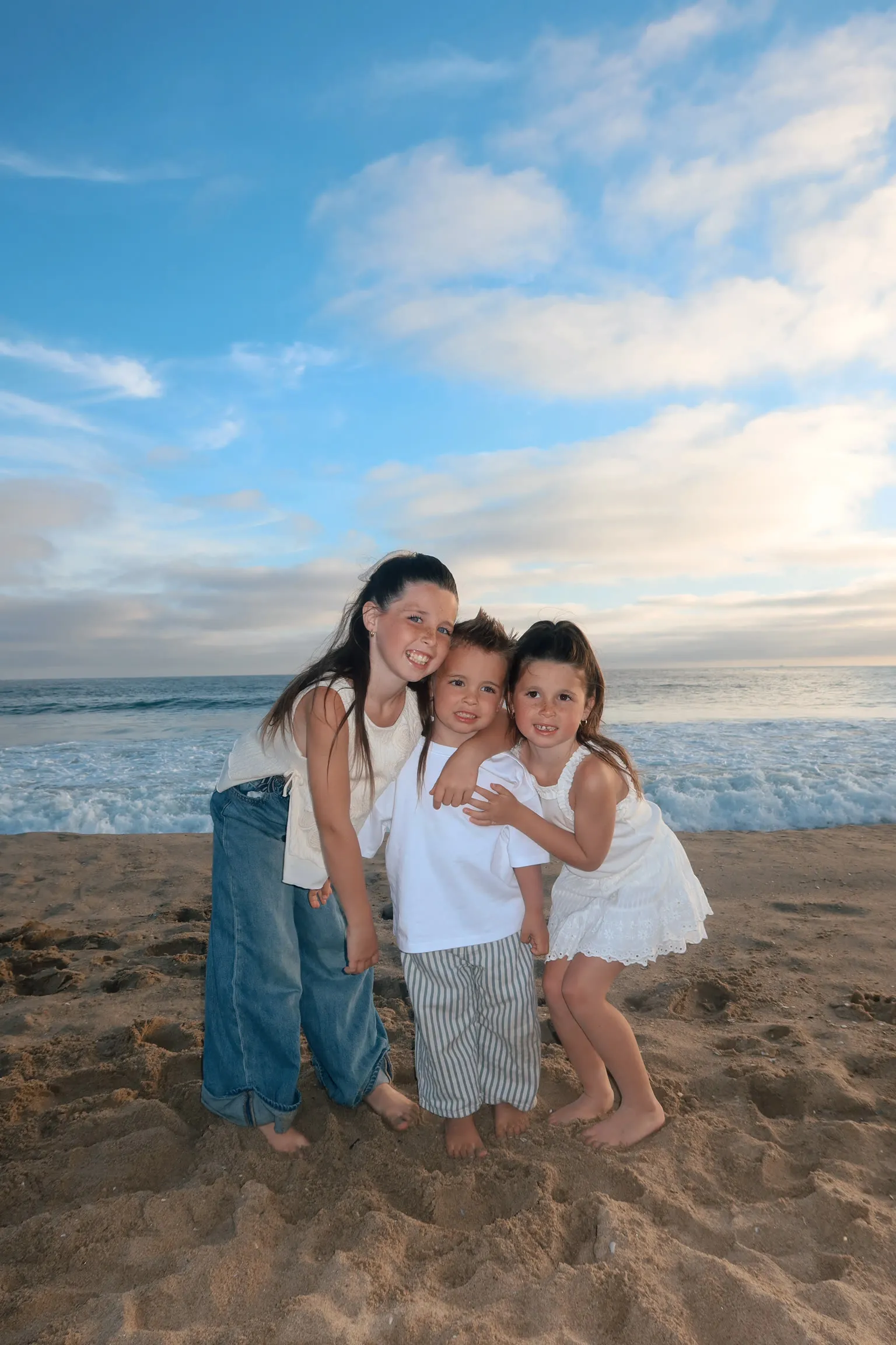 Amelia, Hallie and Hudson hugging on the beach at sunset