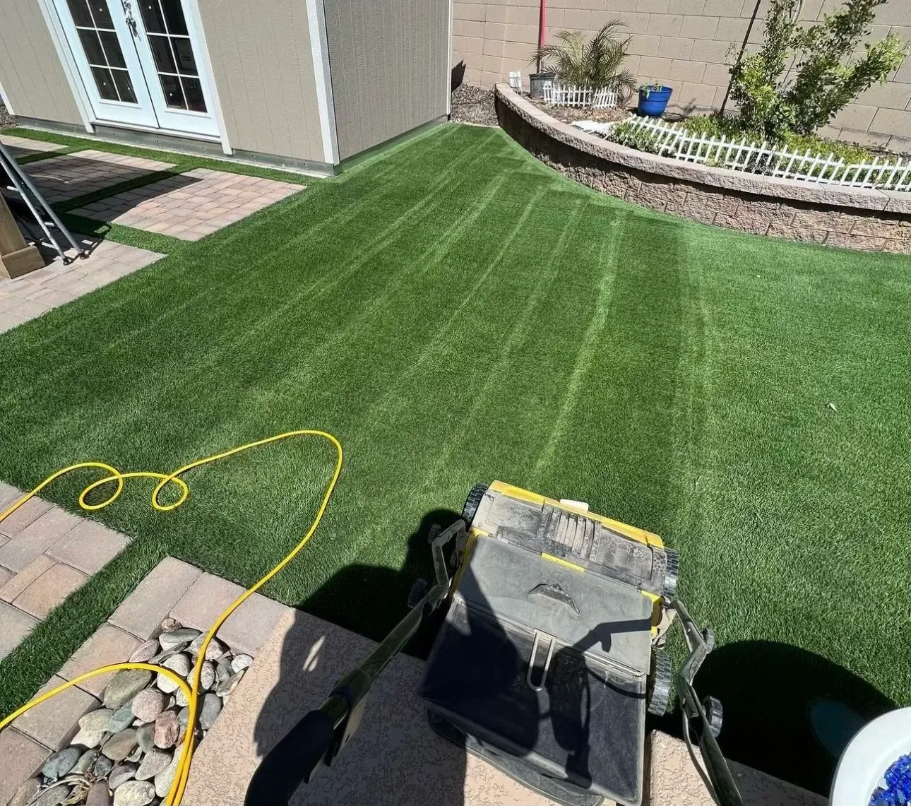 Turf cleaning machine working across a synthetic lawn